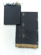 Folded charcoal black handwoven Matka silk suit fabric with gold and red woven bootis paired with a matching tissue border dupatta with fringe tassels on a plain background