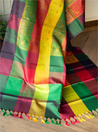 Close-up shot of a handwoven multicolor brocade silk saree displaying a checkered body pattern in red, green, purple, and yellow, complemented by fine zari woven panels and colorful fringed tassels along the edge.