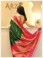 Back view of a model showcasing the vibrant pink and gold zari pallu drape of a handwoven dark green Mysore silk saree.