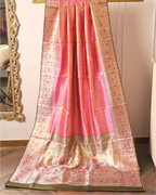 Handwoven pink tissue Patola Kanjivaram silk saree with intricate floral motifs and silver zari border draped indoors next to a mirror.