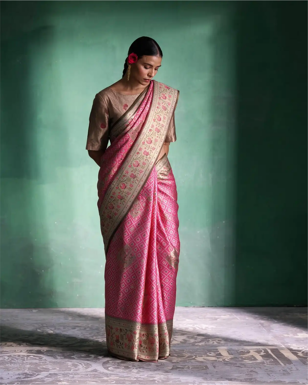 Woman wearing a handwoven pink tissue Patola Kanjivaram silk saree with silver zari border and a beige blouse.