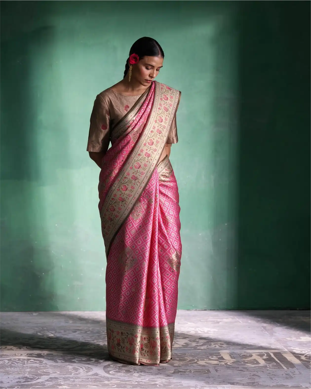 Woman wearing a handwoven pink tissue Patola Kanjivaram silk saree with silver zari border and a beige blouse.