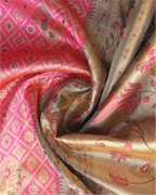 Close-up shot showing the shimmering texture of a handwoven pink tissue Patola Kanjivaram silk saree with intricate gold floral zari pallu and geometric woven motifs