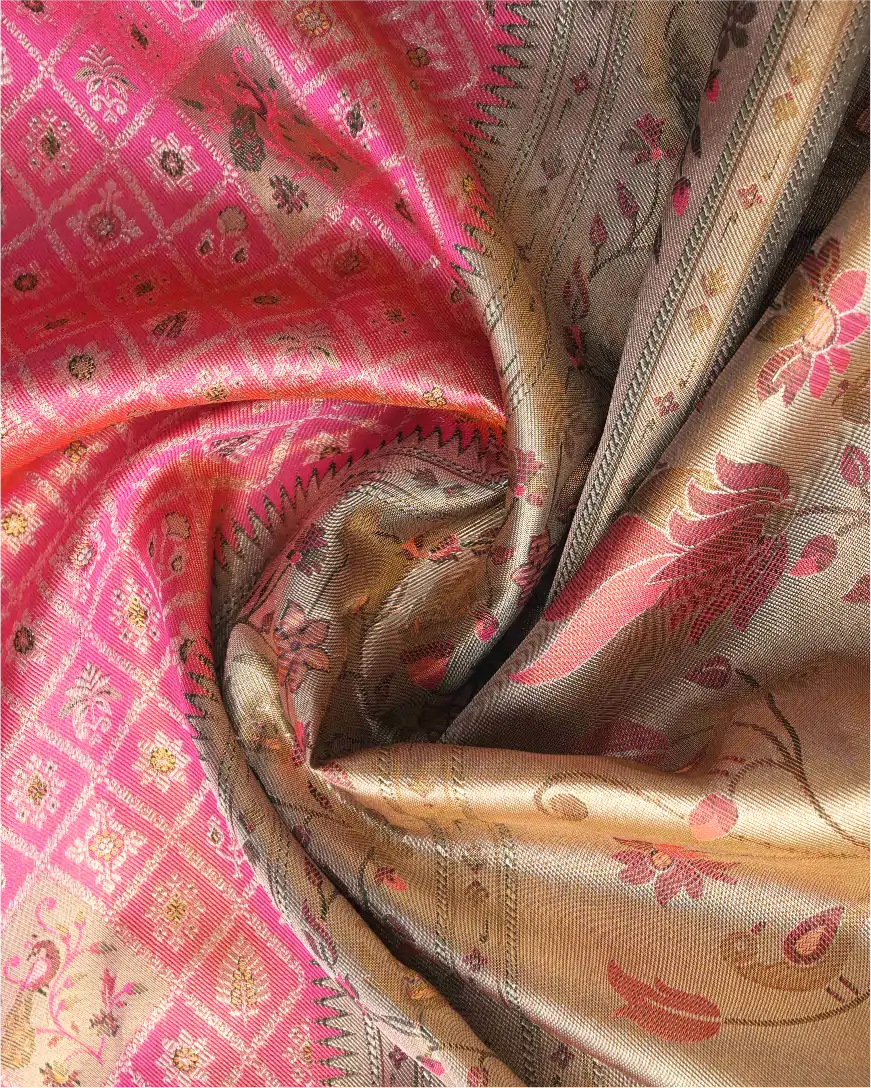 Close-up shot showing the shimmering texture of a handwoven pink tissue Patola Kanjivaram silk saree with intricate gold floral zari pallu and geometric woven motifs