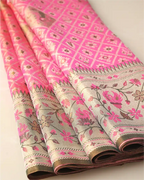 Close-up of folded pink tissue Patola Kanjivaram silk saree showing intricate silver zari geometric motifs and floral border.
