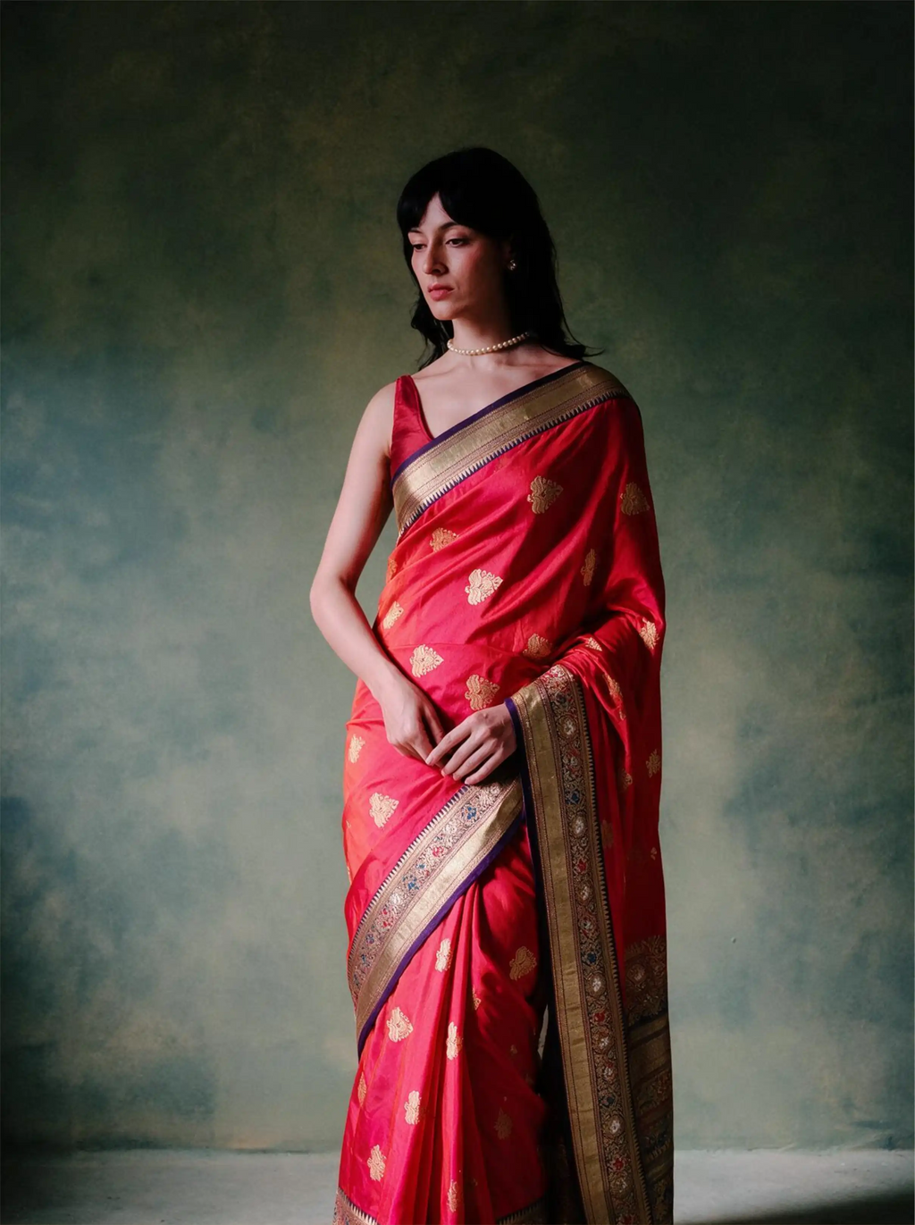 Woman modeling a handwoven pure Katan silk red saree with gold zari motifs and ornate border.