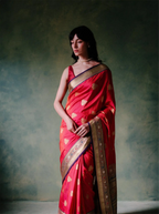 Woman modeling a handwoven pure Katan silk red saree with gold zari motifs and ornate border.