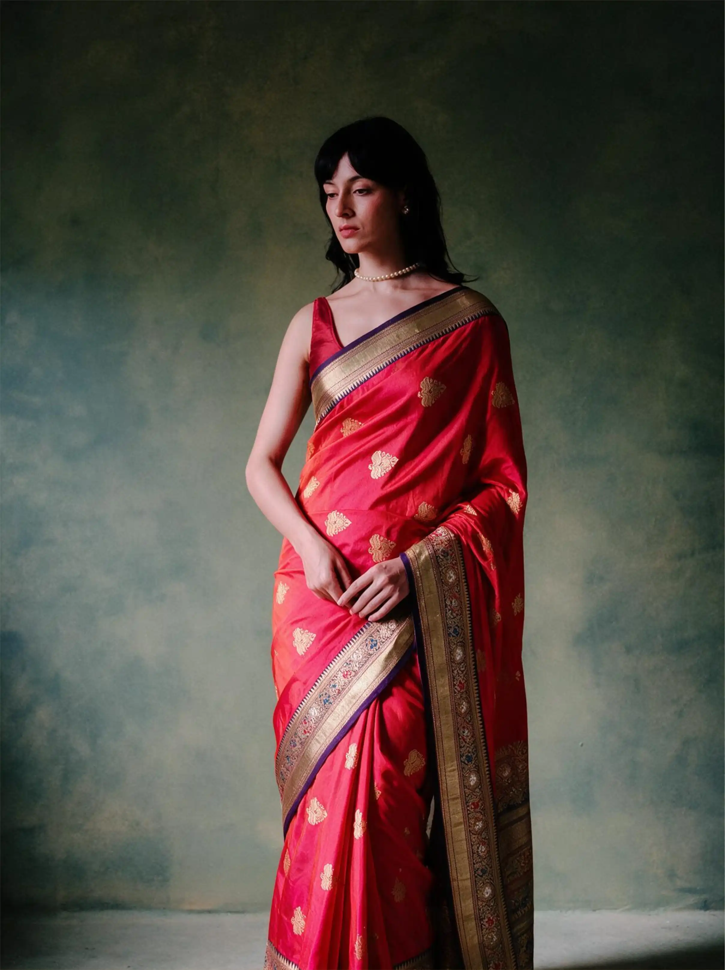 Woman modeling a handwoven pure Katan silk red saree with gold zari motifs and ornate border.