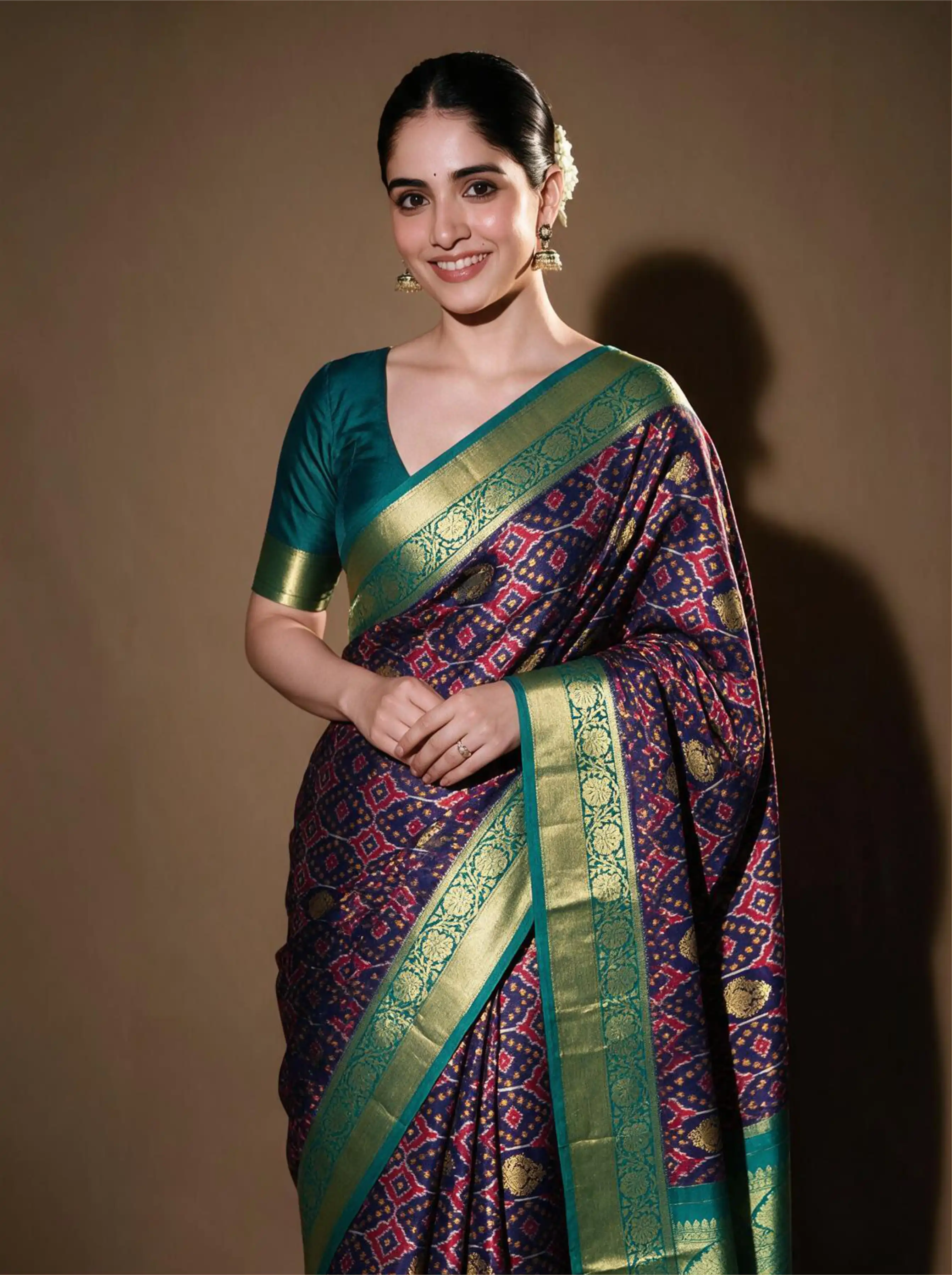 Woman modeling a handwoven purple and green Patola Kanjivaram silk saree with gold zari border and teal blouse.
