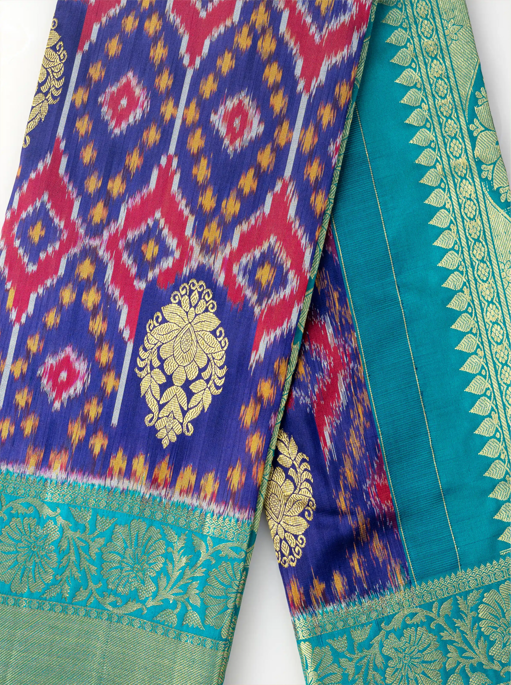 Detailed view of handwoven purple Patola silk saree with vibrant red and yellow geometric ikat motifs and a teal green gold zari border.