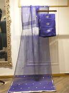 Sheer royal blue handwoven silk dupatta with silver zari bootis and tissue borders, displayed vertically alongside folded suit fabric on a wooden hanger near an ornate gold mirror