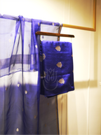 Royal blue handwoven silk suit fabric with gold zari motifs folded on a wooden hanger, paired with a matching sheer dupatta featuring silver zari bootis and tissue borders, set near an ornate gold mirror