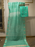 Sheer seafoam green handwoven silk dupatta with gold zari striped pattern and geometric motifs, displayed vertically alongside folded suit fabric on a wooden hanger near an ornate gold mirror
