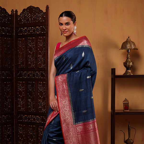 Side profile view of the handwoven Indigo Harmony silk saree showcasing the flowy drape and geometric patterns next to a decorative wooden screen.