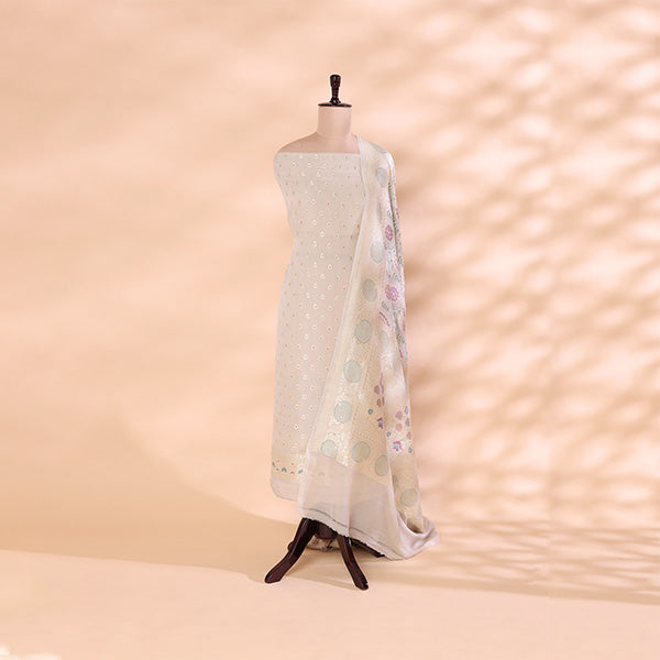 An ivory pure georgette silk suit material featuring intricate Meena and Resham handloom work, paired with a vibrant multicolored harmony dupatta on a mannequin.