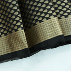 Close-up texture view of the Ivory Noir Tanchoi Banarasi Silk Saree fabric, showcasing the intricate handloom Resham weave and geometric patterns.