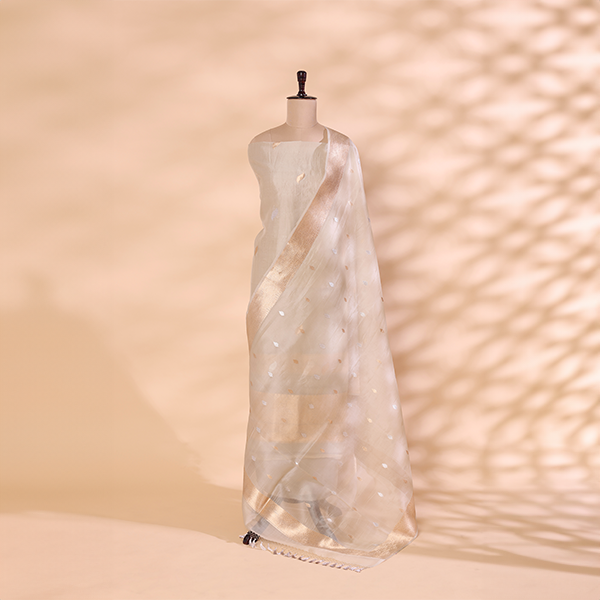 A mannequin displaying an elegant sheer ivory-toned Banarasi silk saree, featuring delicate gold thread embroidery and an ethereal, lightweight drape.