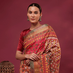 A woman modeling a Kaleidoscope Kantha Tussar Silk Saree with multicolored geometric patterns and a matching blouse against a maroon background.