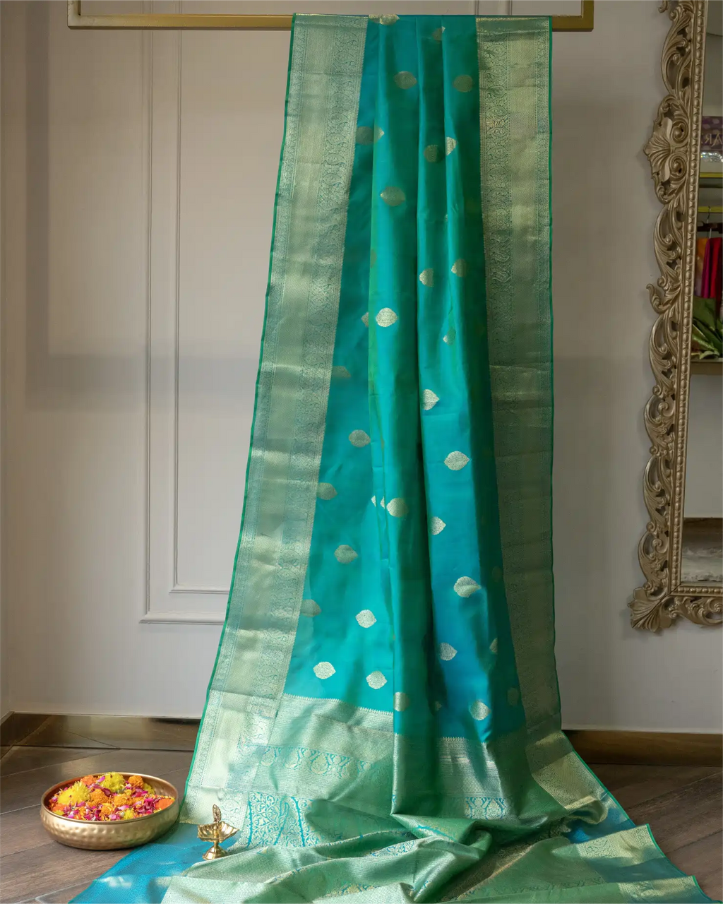 Close-up of the broad, authentic Kanjivaram woven gold zari border on a dark teal silk saree.