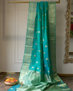 Close-up of the broad, authentic Kanjivaram woven gold zari border on a dark teal silk saree.