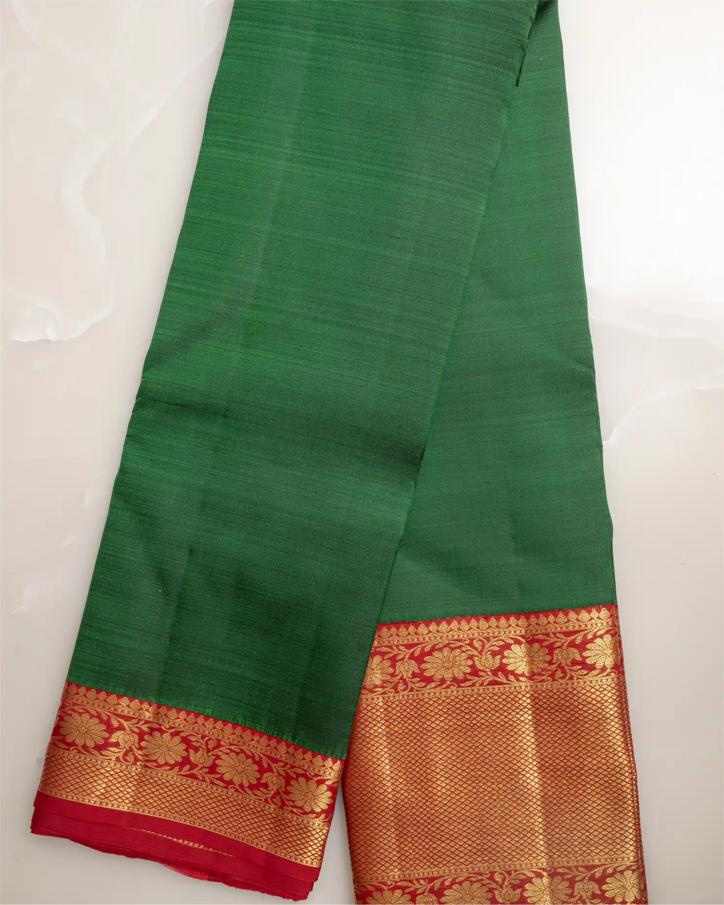 Close-up of the authentic handcrafted gold zari border on an emerald green Kanjivaram silk saree.