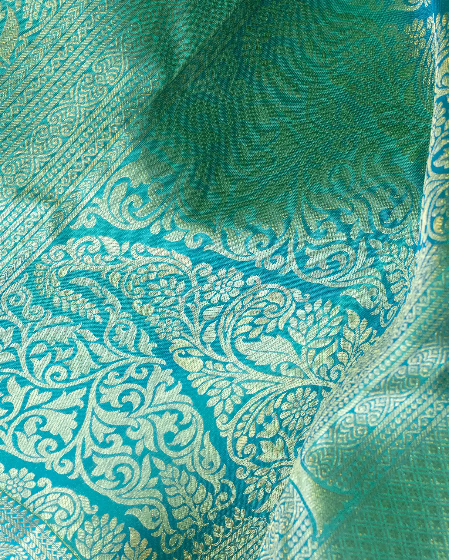 Detailed view of the intricate gold zari buti motifs spread across the dark teal pure silk fabric.
