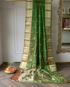 Close-up of intricate gold zari buti motifs woven into the olive green silk saree.