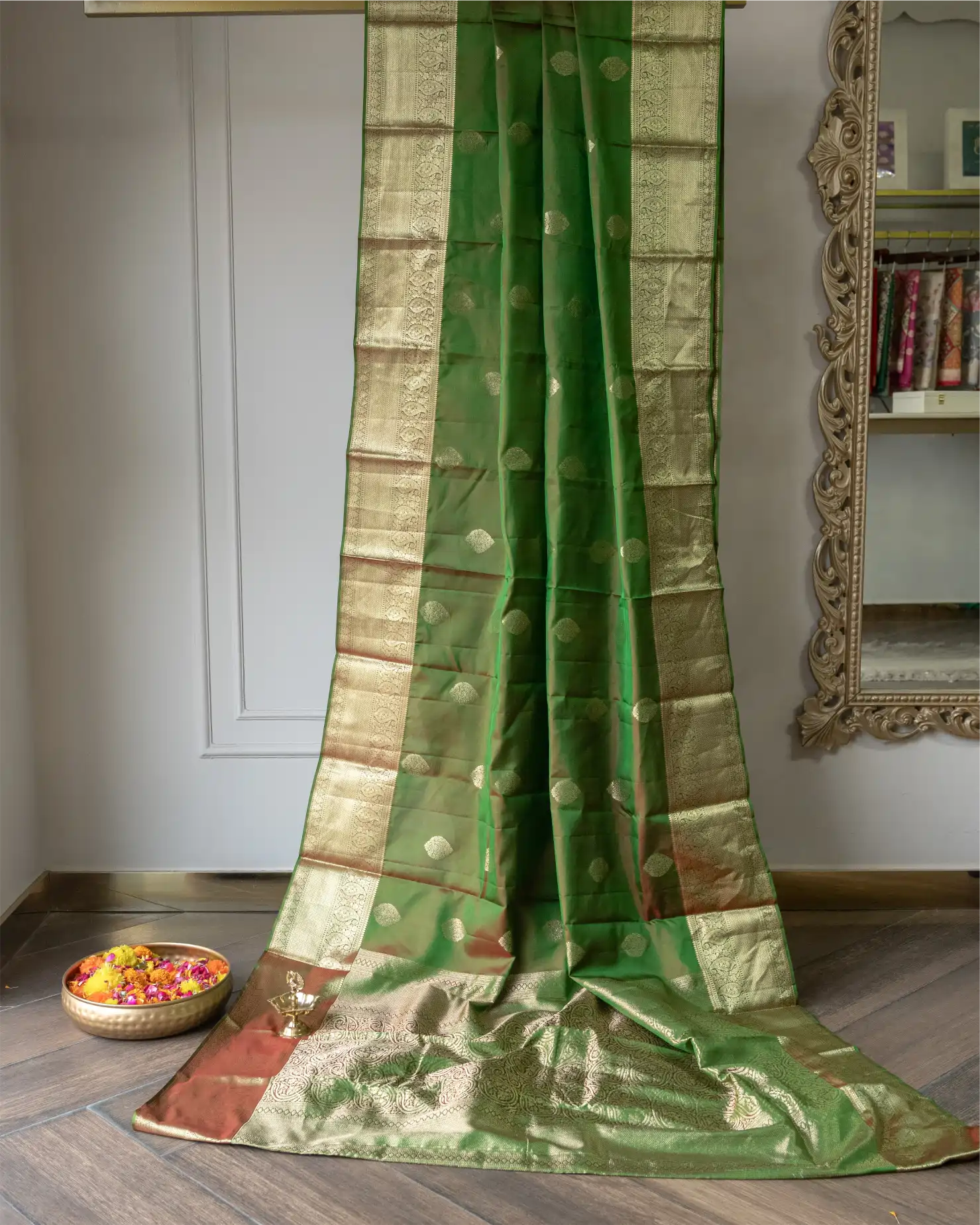 Close-up of intricate gold zari buti motifs woven into the olive green silk saree.