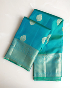 A full-length view showcasing the graceful drape and regal silhouette of the dark teal Kanjivaram saree.