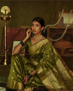 Close-up of the authentic handcrafted gold zari border on an olive green Kanjivaram silk saree.