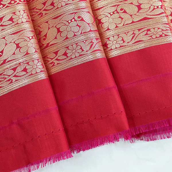 Flat lay or close-up of the unstitched pure red silk blouse fabric featuring a matching gold zari border.