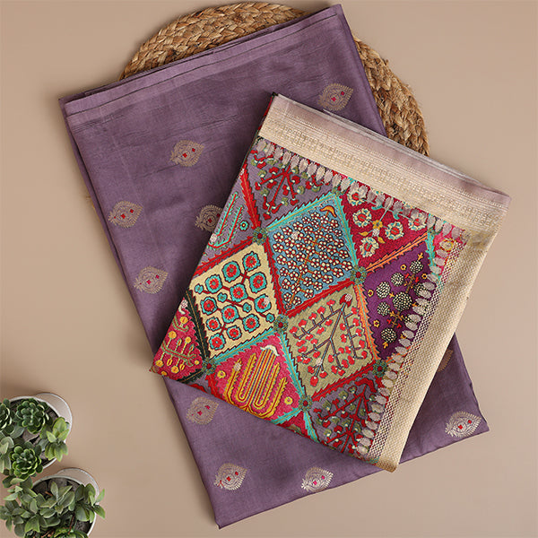 A flat-lay view of an elegant light purple handwoven silk suit set, paired with a vibrant, multicolored traditional dupatta featuring intricate patterns and a delicate gold zari border.