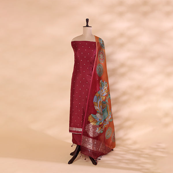 Unstitched unpolished Banarasi silk suit fabric in a vivid magenta hue, laid out to show the rich handwoven texture for the kurta and bottom pieces.