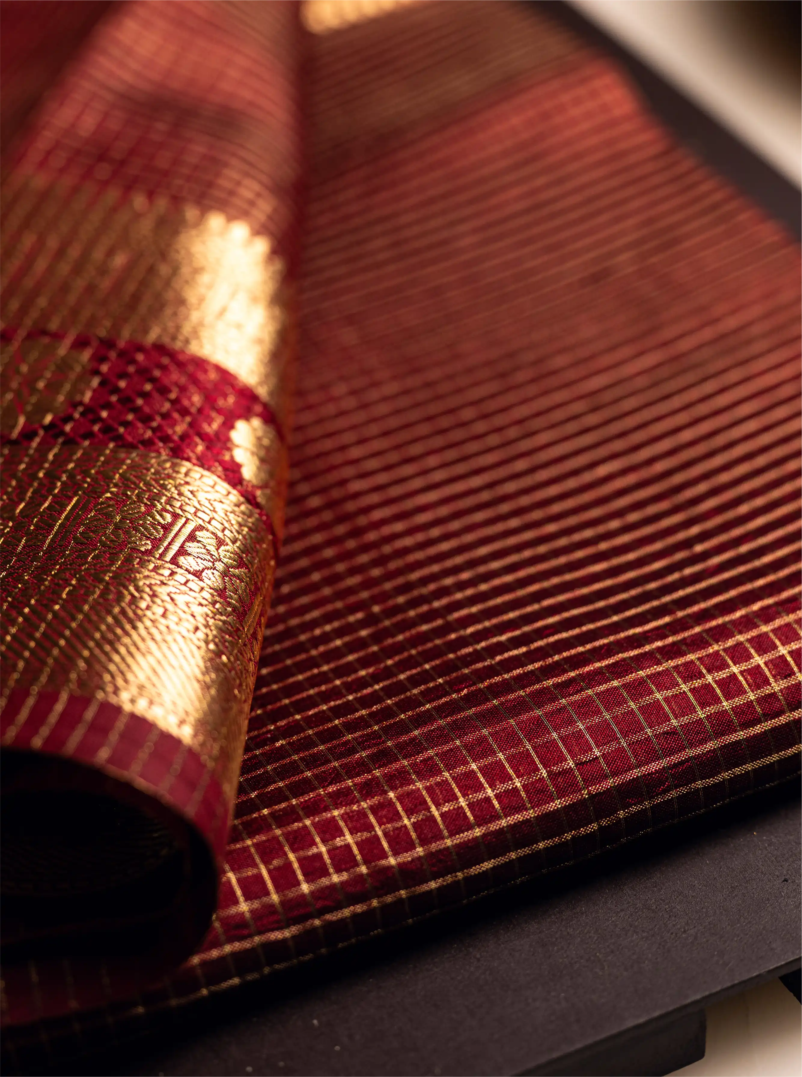 Close-up of a maroon Katan silk saree showing a large handwoven gold zari floral motif (buta) and a rich traditional border