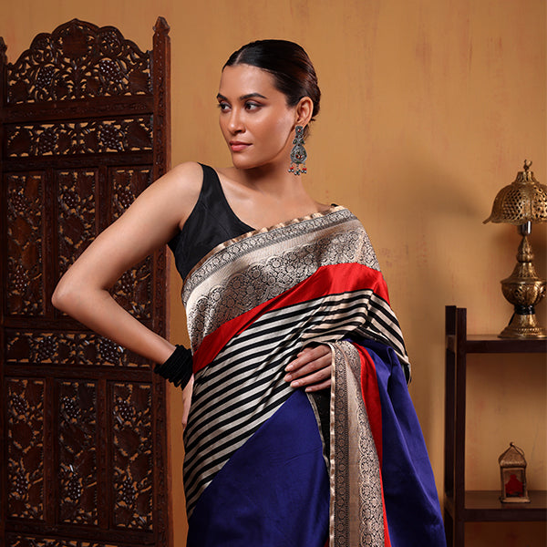 Midnight blue-black striped pure handwoven Banarasi Satin Silk saree featuring heavy gold zari borders and elegant tassels on a mannequin.