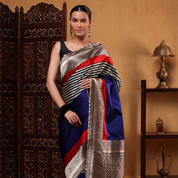 Model wearing the Midnight Majesty blue-black striped Banarasi Satin Silk saree, showcasing the rich drape, red accent pleats, and gold zari border.
