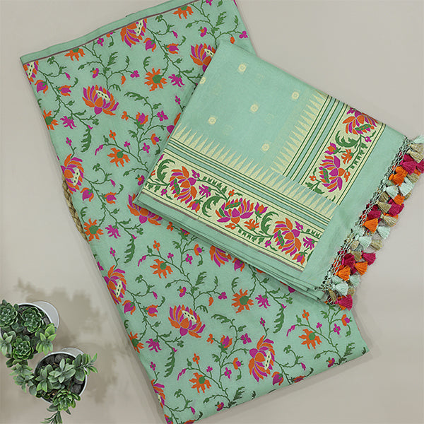 A beautiful flat-lay of a mint-green silk suit set, featuring vibrant floral patterns, a decorative border, and elegant tassels on the dupatta.