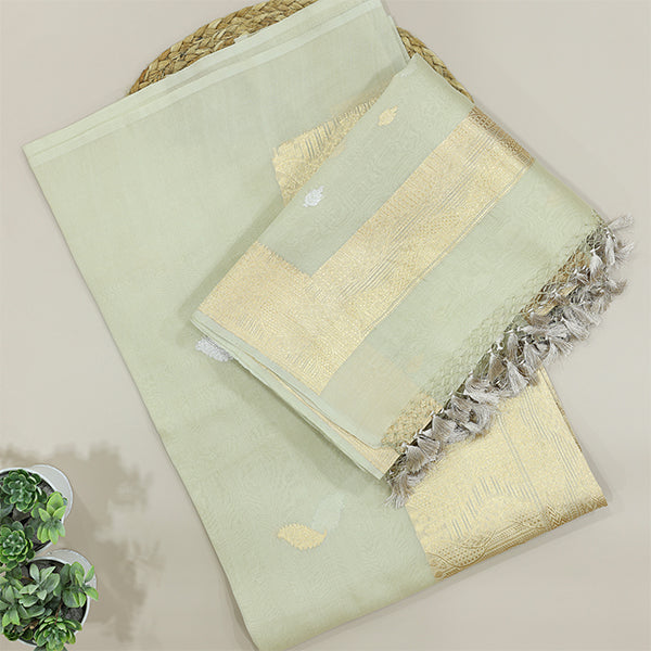 A flat-lay view of a sophisticated mint green handwoven silk suit set, featuring an elegant gold zari border, delicate floral motifs, and detailed tassels.