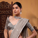A detailed presentation layout of the saree's stunning gold and silver zari border contrasting against the serene grey cotton fabric.