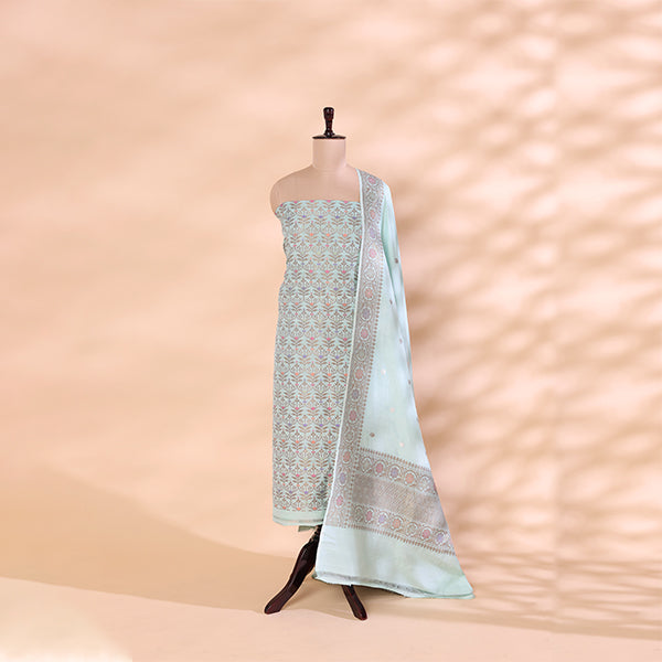 A mannequin displaying a premium moonlit silver Munga silk unstitched suit with an intricate Zari and Resham work neckline, paired with a vibrant multicoloured kaleidoscope horizon dupatta.