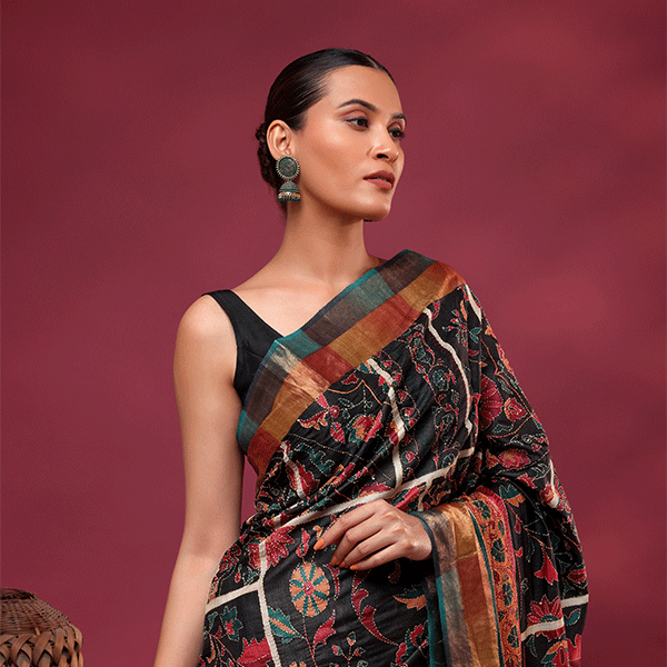 A woman modeling a natural ivory pure Tussar silk saree with an intricate multi-colored handwoven Kantha embroidery pallu.