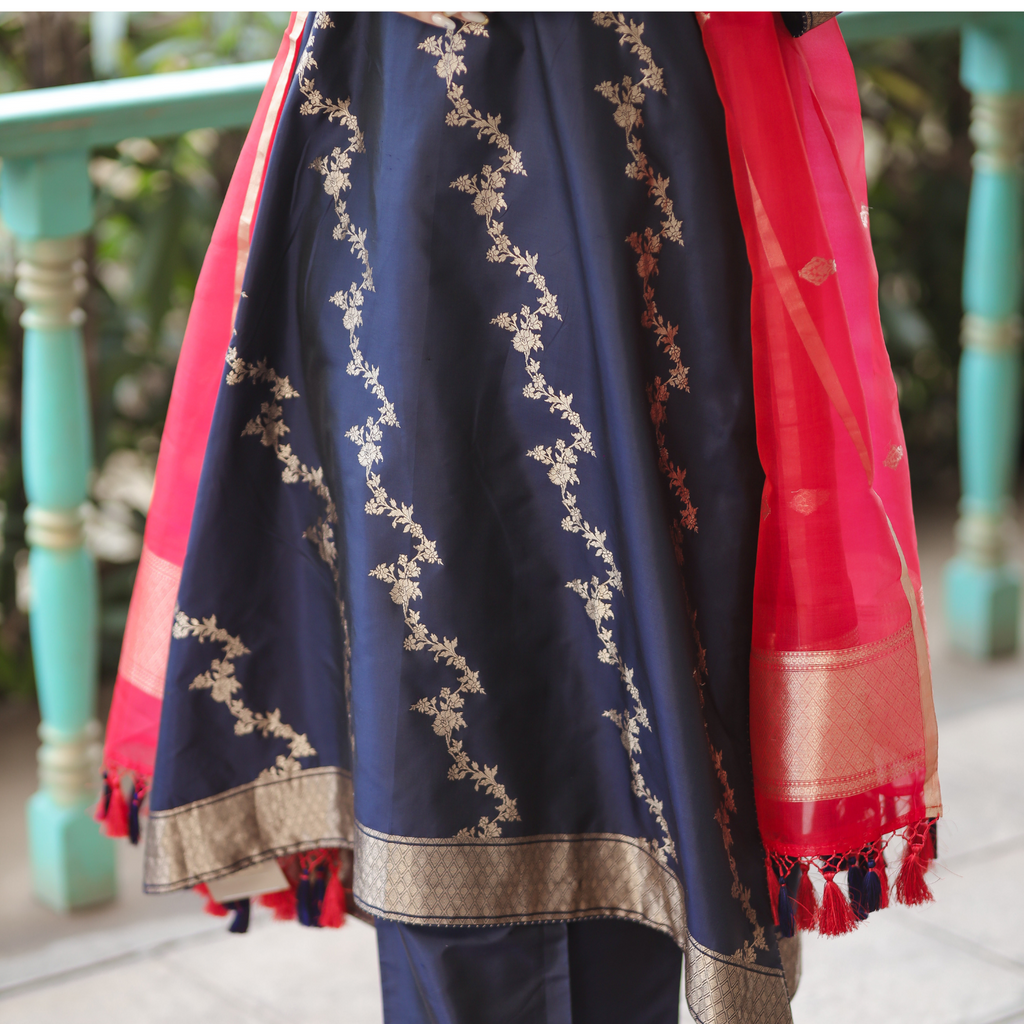 Close-up of a Navy Blue Banarasi Silk Kurta featuring intricate gold zari floral embroidery and a red Kora silk dupatta with tassels.