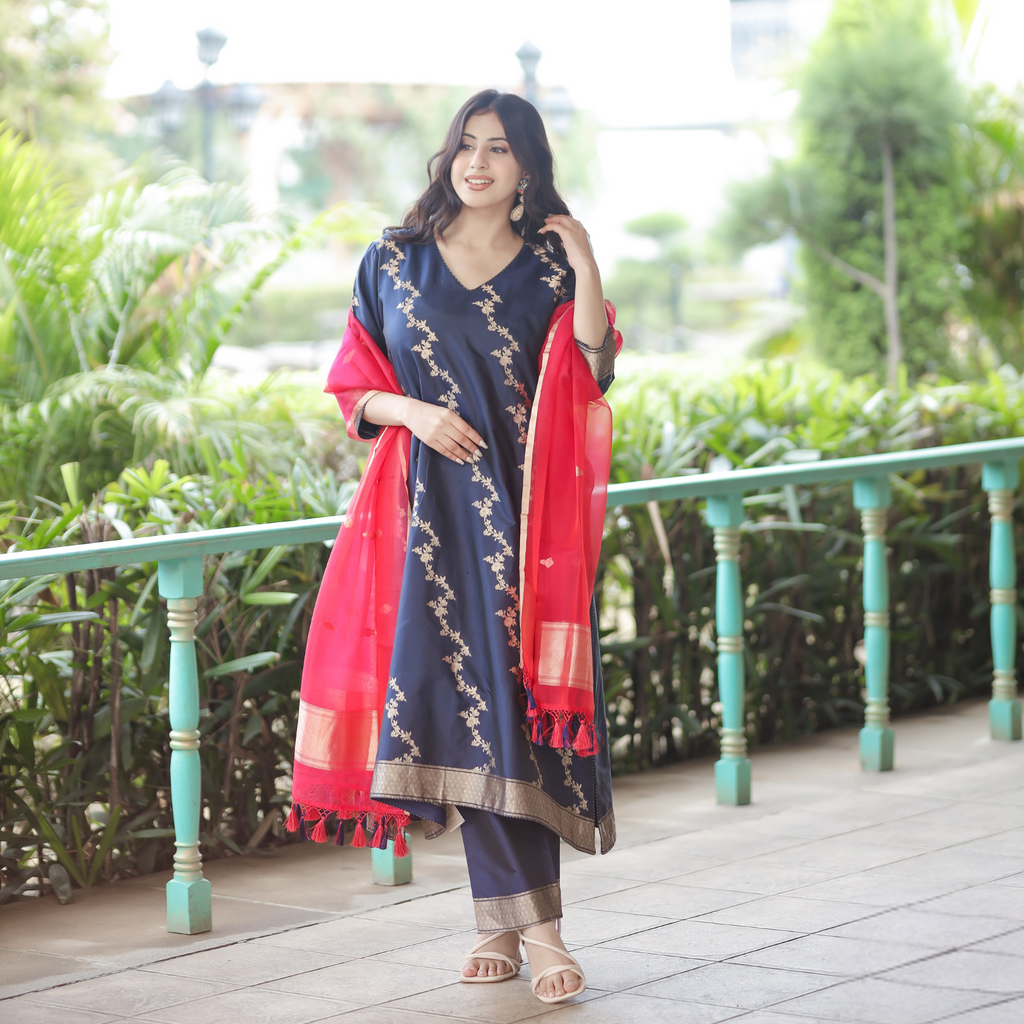 Model wearing a Navy Blue Handwoven Banarasi Silk Suit with gold zari embroidery and a contrasting Red Kora Silk Dupatta in an outdoor setting.