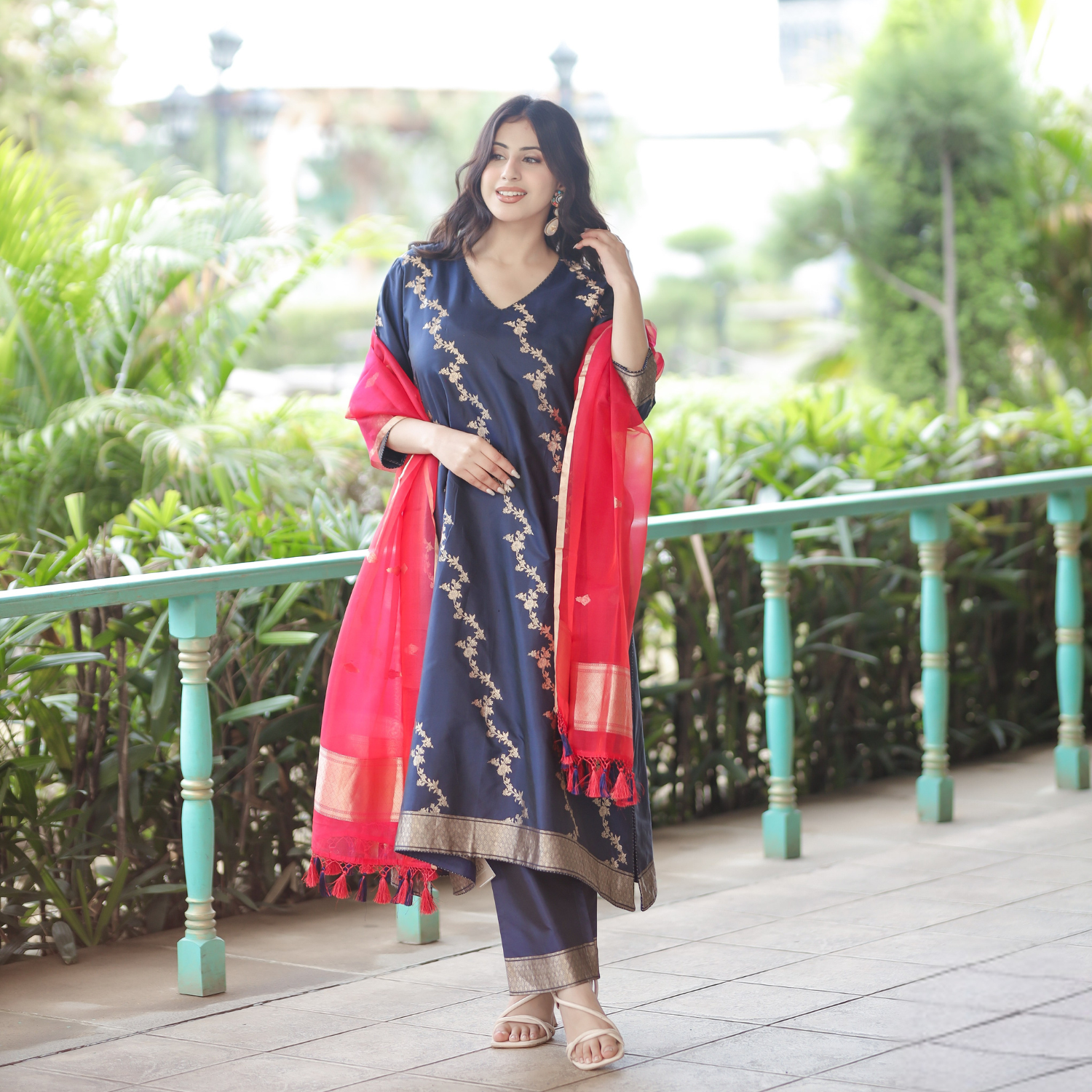 Model wearing a Navy Blue Handwoven Banarasi Silk Suit with gold zari embroidery and a contrasting Red Kora Silk Dupatta in an outdoor setting.