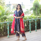 Full-length outdoor view of a Navy Blue Handwoven Banarasi Silk Suit with 3/4 sleeves, gold zari work, and a contrast Red Kora Silk dupatta.