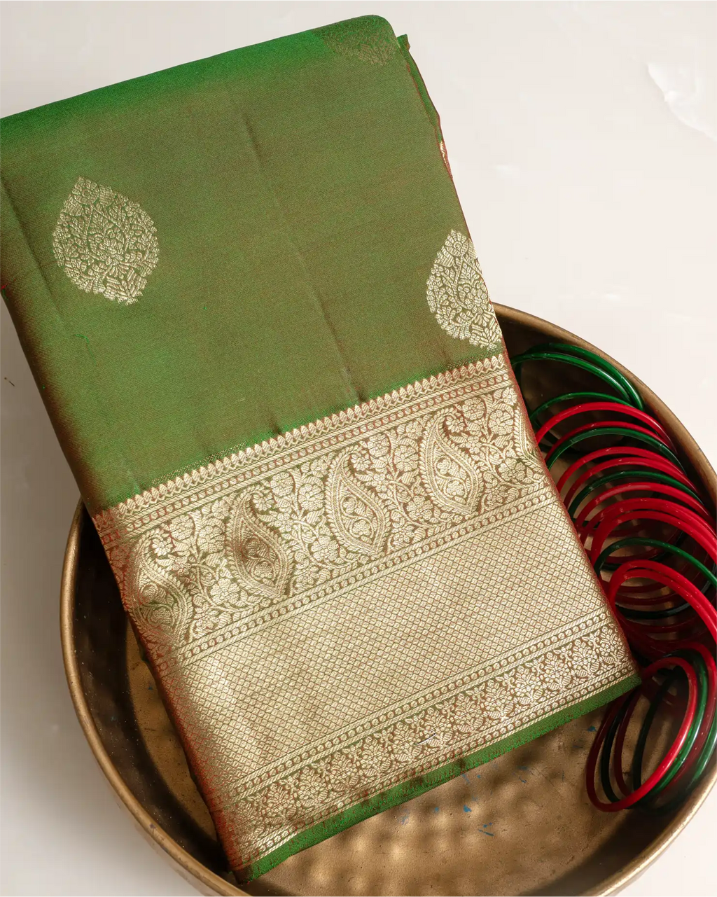 A full-length view of the olive green Kanjivaram silk saree, highlighting its graceful drape and silhouette.