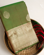 A full-length view of the olive green Kanjivaram silk saree, highlighting its graceful drape and silhouette.