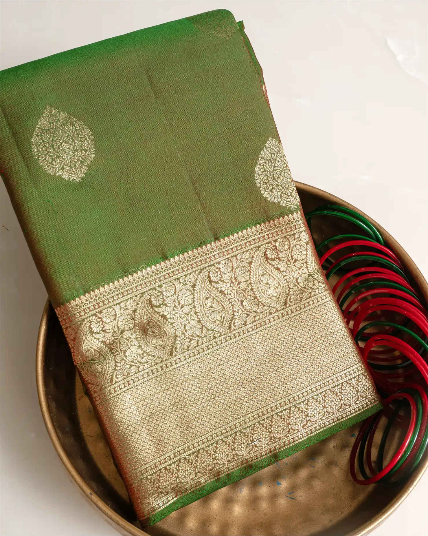 A full-length view of the olive green Kanjivaram silk saree, highlighting its graceful drape and silhouette.