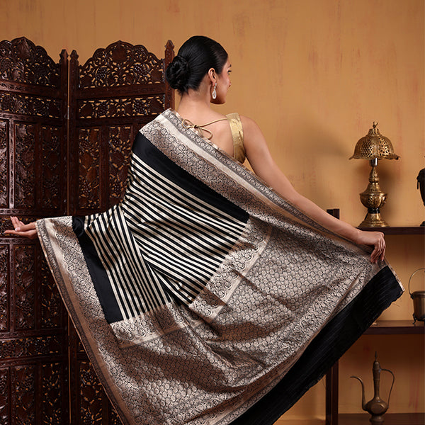 Close-up view of the exquisite, heavy weave gold zari pallu and detailed fringe tassels on the onyx black satin silk saree.
