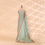 A mannequin showcasing an elegant pastel green handwoven silk suit, featuring delicate floral patterns, intricate zari borders, and a matching dupatta